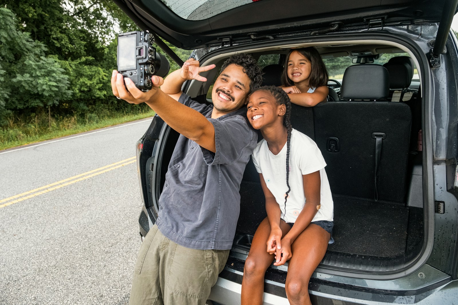 Photo by Samsung Memory US Father and daughters take a selfie by the car.